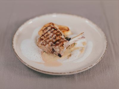 Kalbskrone auf weißem Teller, serviert mit Tramezzini-Flan, Waldpilzen und Parmesanschaum.