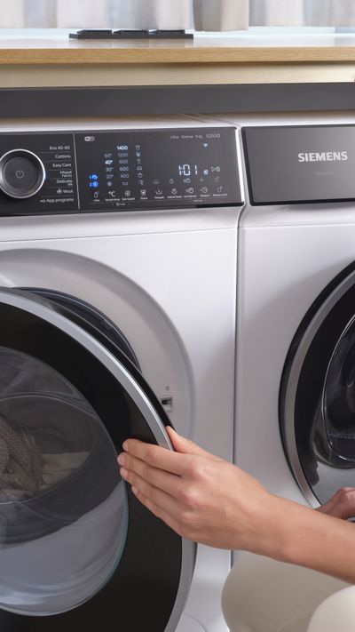vrouw stopt was in de wasmachine met droger