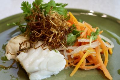 Tallerken med kokt fisk, strimlede gulrøtter, grønt og sprøstekt garnityr.