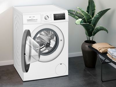 Pesukone avonaisella ovella modernissa kylpyhuoneympäristössä. 