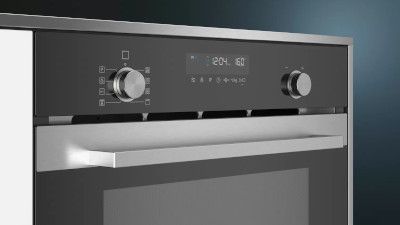 Forno in acciaio inox con display digitale e manopole di controllo su sfondo scuro.
