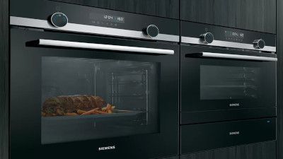 eleganti forni neri Siemens impilati con cibo visibili all'interno del forno, dimostrazione del moderno design della cucina.