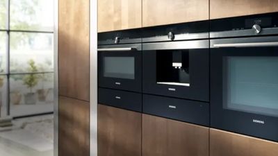 Cucina moderna con eleganti elettrodomestici Siemens da incasso in nero e mobili in legno.