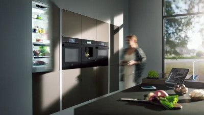 Cucina moderna con elettrodomestici, controsoffitto e persona sfocata in movimento.