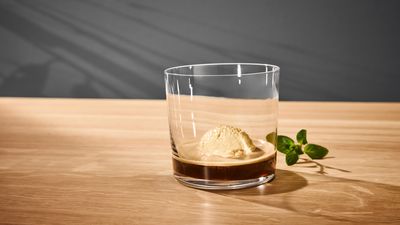 Une boule de glace vanille dans un verre d'expresso, sur une table en bois avec une garniture à la menthe.