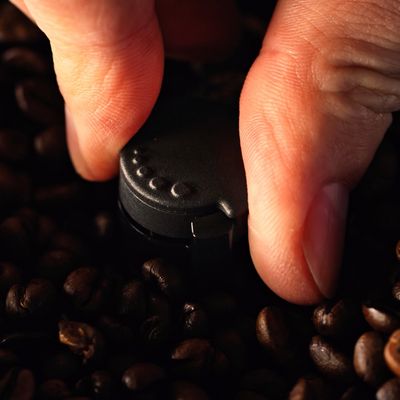 Een close-up van iemand die met zijn vingers de keuzeschijf voor de maalgraad draait op een volautomatische espressomachine van Siemens.