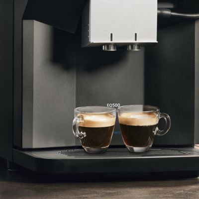 Twee versgezette Americano's onder de koffiedispenser van een volautomatische espressomachine van Siemens.
