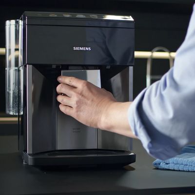 La main d'une personne réglant la buse d'écoulement du café d'une machine à café automatique Siemens.