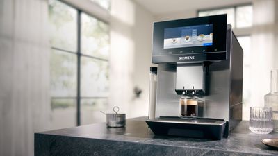 Eine Person l&auml;sst hei&szlig;es Wasser aus einem Siemens Kaffeevollautomaten mit Teefunktion.