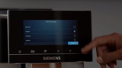 Un doigt sélectionnant une langue sur l'interface de l'écran tactile d'une machine expresso automatique Siemens.