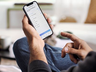 Primo piano di un uomo che guarda lo smartphone seduto in salotto.