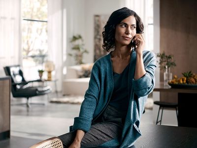 Eine Frau in einem Wohn-Essbereich telefoniert mit ihrem Handy.