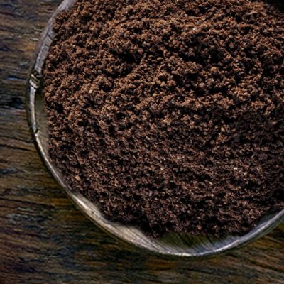 Une grande cuillère en bois remplie de café moulu. 