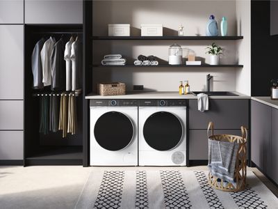 Eine Waschmaschine und ein Trockner stehen in einem gut organisierten Waschraum mit Regalen und Platz, um saubere Wäsche aufzuhängen.
