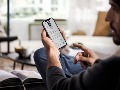 Nahaufnahme eines Mannes, der in einer Lounge sitzt und auf ein Handy schaut.