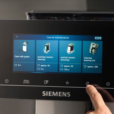 Un doigt effleure l'écran tactile d'une machine à café Siemens, dans la section Entretien & Maintenance du menu sur l'écran.