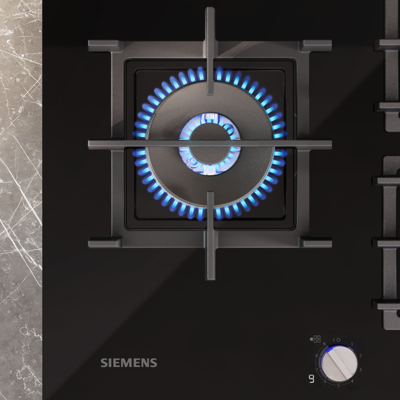 Widok z góry na zapalony palnik na gazowej płycie grzewczej marki Siemens.