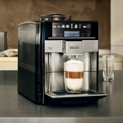 Une machine à café Siemens EQ6 plus sur un comptoir avec un latte macchiato sous le distributeur.