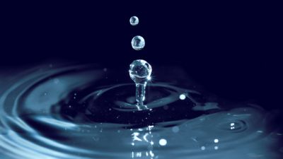 Des gouttes d'eau  tombent et provoquent des ondulations sur une surface liquide.