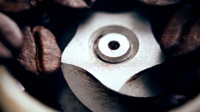 Gros plan sur un broyeur de café professionnel en train de moudre des grains de café.