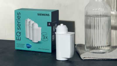 Een koffiemachine-waterfilter op een werkblad naast de verpakking en een waterkan.