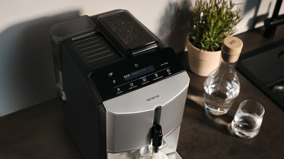 Vue de dessus d'une machine expresso automatique Siemens sur un comptoir de cuisine, à côté d'un verre d'eau.