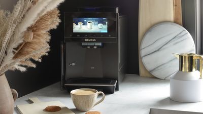 Une machine à café automatique EQ900 sur un comptoir en marbre blanc, à côté du café et des biscuits.