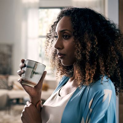 Plan rapproché d'une femme sirotant un café dans une tasse en porcelaine dans un salon moderne et élégant. 