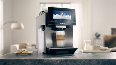 Une machine à café EQ900 sur un comptoir en marbre bleu avec un latte macchiato sous le distributeur.