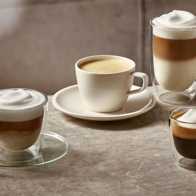 Assortiment de boissons &agrave; base de caf&eacute; et assiette de mignardises pos&eacute;s sur une surface gris clair.&nbsp;