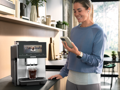 Een vrouw in sportkleding zet koffie met haar EQ900 machine via een smartphone.
