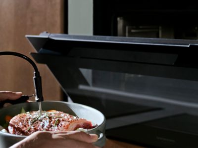 יד מקיימת אינטראקציה עם מסך מגע אלגנטי בתנור מודרני, ובוחרת באפשרות השחמה אישית לבישול.