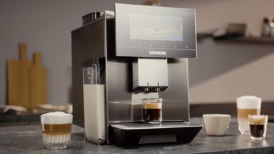 Machine &agrave; caf&eacute; Siemens pr&eacute;parant un expresso sur le plan de travail d'une cuisine moderne. Tout autour sont pos&eacute;es d'autres sp&eacute;cialit&eacute;s &agrave; base de caf&eacute;.