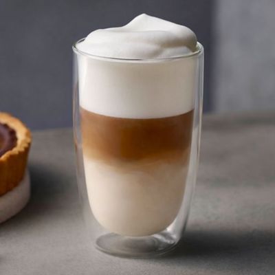 Un grand verre de café au lait avec de la crème fouettée et un dessert au chocolat cuit à côté.
