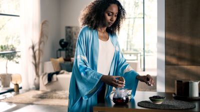 Verschiedene Gef&auml;&szlig;e sind mit verschiedenen Teesorten bef&uuml;llt. Dazwischen liegen mehrere kleine L&ouml;ffel.