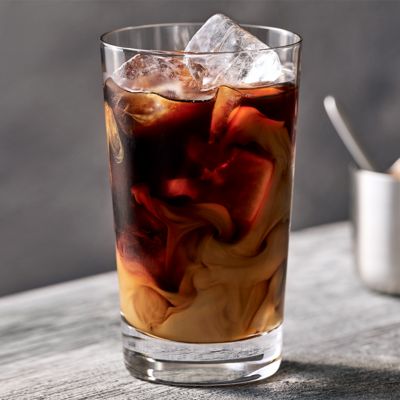Un café frappé dans un verre avec de la glace placée sur une ardoise en pierre.