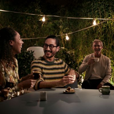 Een groep vrolijk pratende en lachende mensen aan tafel die koffie drinken. 