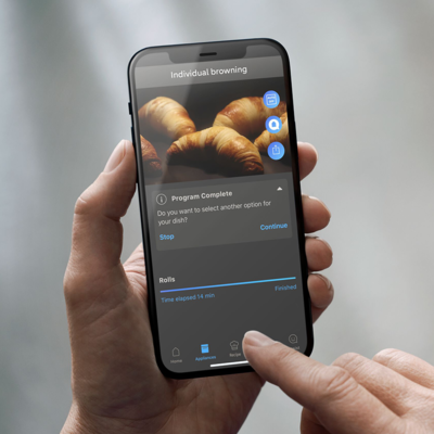 Uno smartphone mostra la foto di alcuni croissant in cottura all'interno di un forno Siemens iQ700.
