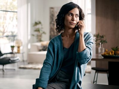 Eine stilvolle Frau telefoniert entspannt in einer modernen, lichtdurchfluteten Wohnung mit elegantem Interieur.