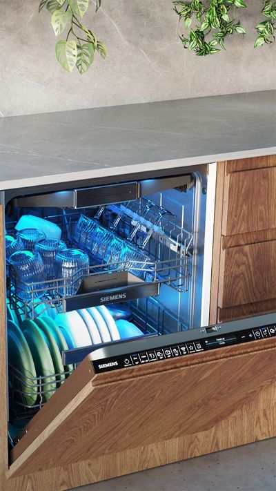 Ein offener Siemens Einbau-Geschirrspüler mit blauer Innenbeleuchtung in einer modernen Küche mit Holzfronten und Edelstahl-Arbeitsplatte