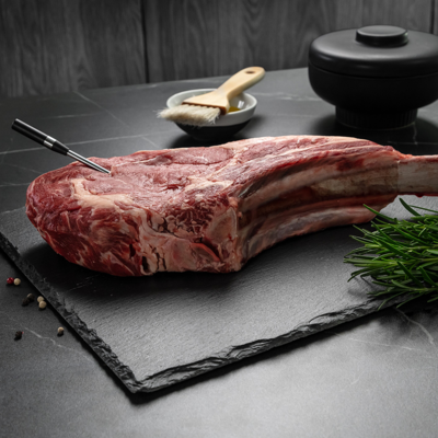  Surowy stek T-bone na kuchennym blacie z umieszczoną w nim bezprzewodową termosondą.