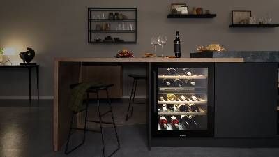 Una cucina moderna con un frigorifero per vino, un piano in legno e sgabelli da bar eleganti.