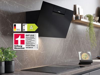 Eine elegante schwarze Dunstabzugshaube an einer Marmorwand mit Effizienzangaben und einer Digitalanzeige auf einem Tablet auf der Arbeitsplatte in der Nähe.