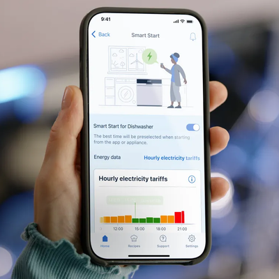 Eine Hand hält ein Smartphone, auf dem die smartStart Funktion in der Siemens Hausgeräte App angezeigt wird.