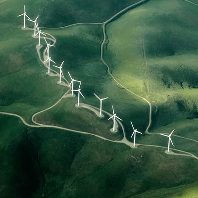 Widok z góry na turbiny wiatrowe na zielonym polu, produkujące energię odnawialną.