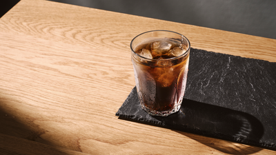 Un café infusé à froid dans un verre avec de la glace placée sur une ardoise en pierre.