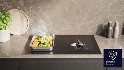 InductionAir Plus -induktionskogeplade i grå bordplade, madlavning på kogepladen. Diamond Protect-logo oven på billedet.