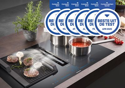 Keuken met grill en pannen, steaks en sauzen. Meerdere "Best in Test"-prijzen zichtbaar.