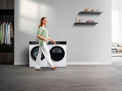 Moderní prádelna s elegantní pračkou a sušičkou, žena v ležérním oblečení.