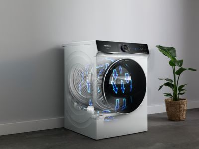 Uma máquina de secar roupa Siemens com uma ilustração da dinâmica do fluxo de ar, ao lado de um vaso de plantas contra uma parede neutra.